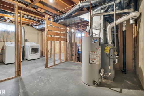 The property features an unfinished basement with exposed wooden framing and overhead joists, a water heater, and a furnace - 585 Knottwood Road W, Edmonton, AB - Indoor Photo Showing Basement