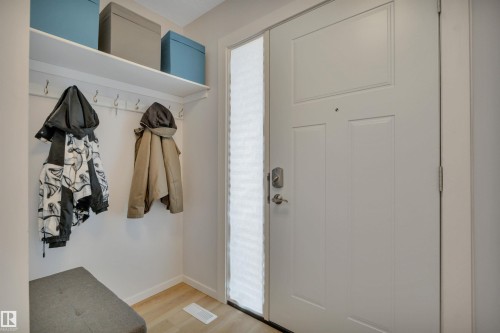 Entryway featuring a white paneled door with a sidelight, a coat rack with a shelf, and light-toned flooring - 585 Knottwood Road W, Edmonton, AB - Indoor Photo Showing Other Room