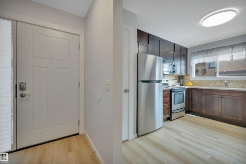 The kitchen features dark wood cabinetry, a stainless steel refrigerator, and a stainless steel oven/range with a microwave above - 585 Knottwood Road W, Edmonton, AB - Indoor Photo Showing Kitchen