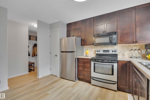 The kitchen features dark wood cabinetry, stainless steel appliances, and light-colored countertops - 585 Knottwood Road W, Edmonton, AB - Indoor Photo Showing Kitchen