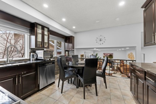 Kitchen with dark wood-finish cabinetry, stainless steel dishwasher, and a deep basin sink with a gooseneck faucet - 16424 106 Street, Edmonton, AB - Indoor