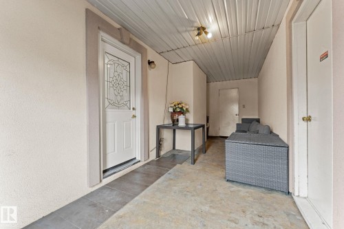 Covered entry area featuring a white paneled door with decorative glass, stucco exterior, and a corrugated metal ceiling - 16424 106 Street, Edmonton, AB - Indoor Photo Showing Other Room