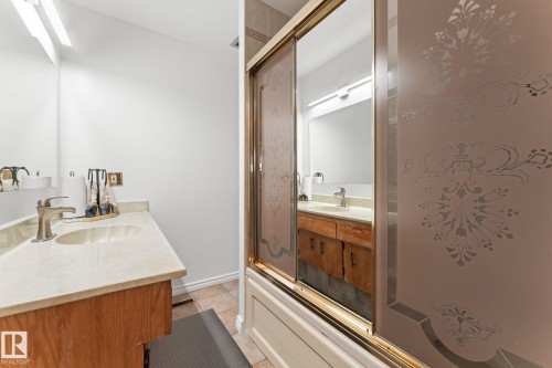 Bathroom featuring a wood-finish vanity with an integrated sink and brushed nickel faucet, a large mirror, and overhead lighting - 16424 106 Street, Edmonton, AB - Indoor Photo Showing Bathroom