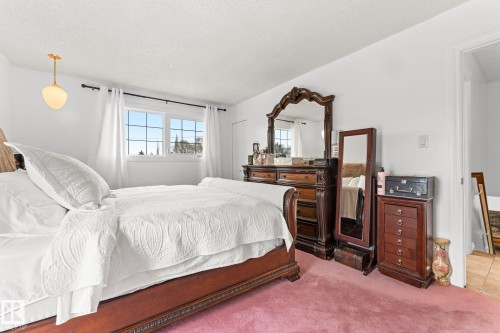 Carpeted room featuring a double window with white trim, a brass-finish ceiling pendant light fixture, and a doorway leading to another area of the property - 16424 106 Street, Edmonton, AB - Indoor Photo Showing Bedroom