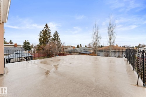 Expansive rooftop deck featuring a stucco exterior wall, wrought iron railing, and a concrete surface - 16424 106 Street, Edmonton, AB - Outdoor