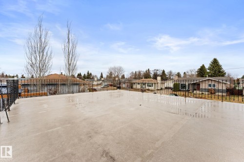 Expansive concrete deck featuring a black metal railing and surrounding neighborhood architecture - 16424 106 Street, Edmonton, AB - Outdoor