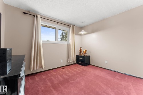 Bedroom featuring a window with white trim, suspended ceiling light, and red carpet - 16424 106 Street, Edmonton, AB - Indoor Photo Showing Other Room