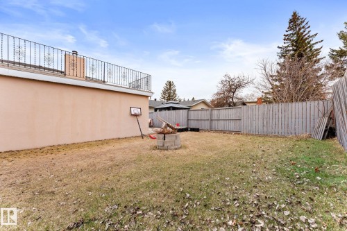 Expansive rear yard featuring a privacy fence, established trees, and a stucco exterior - 16424 106 Street, Edmonton, AB - Outdoor