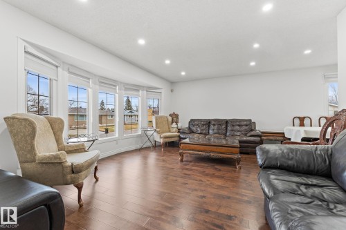 Spacious living area featuring a prominent bay window, recessed ceiling lighting, wood-finish flooring, and crisp white wall paint - 16424 106 Street, Edmonton, AB - Indoor Photo Showing Living Room