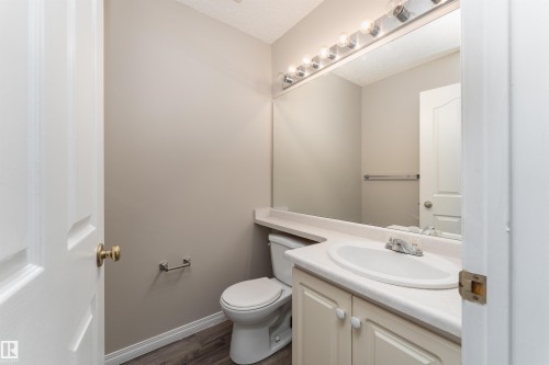 Bathroom featuring a vanity with a white countertop and an integrated sink, a large mirror, and overhead lighting - 3 9703 174 Street, Edmonton, AB - Indoor Photo Showing Bathroom