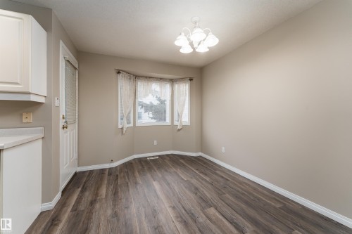This space features durable plank flooring, a bay window with natural light, and a ceiling-mounted light fixture - 3 9703 174 Street, Edmonton, AB - Indoor Photo Showing Other Room