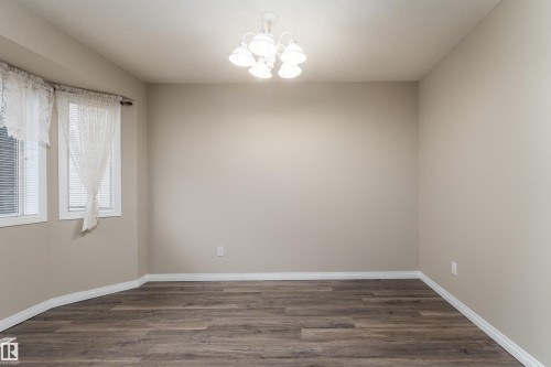 This room features rich wood-style flooring, light-colored walls, and a ceiling light fixture - 3 9703 174 Street, Edmonton, AB - Indoor Photo Showing Other Room