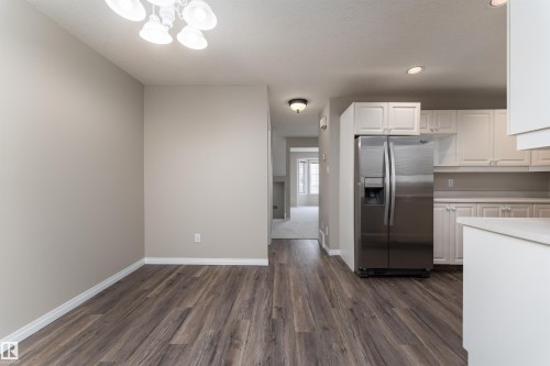 This kitchen features white cabinetry and a stainless steel refrigerator - 3 9703 174 Street, Edmonton, AB - Indoor Photo Showing Kitchen