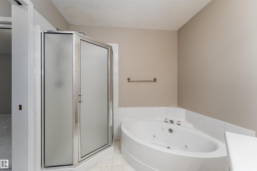 Bathroom featuring a corner shower with a frosted glass door, a corner jetted tub, and a towel bar - 3 9703 174 Street, Edmonton, AB - Indoor Photo Showing Bathroom