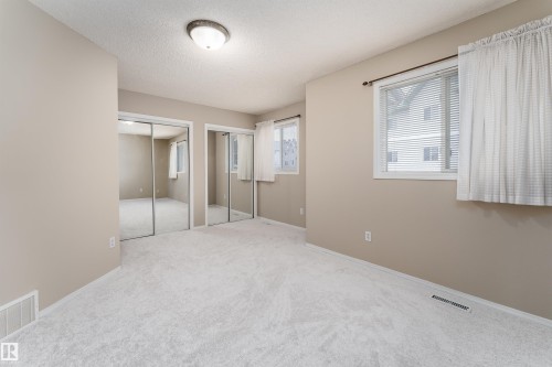 Well-lit interior space featuring light-colored walls and soft carpet flooring - 3 9703 174 Street, Edmonton, AB - Indoor