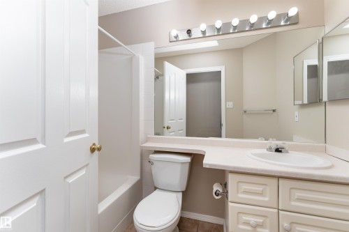 Bathroom featuring a vanity with an integrated sink, a large mirror, and a bathtub with a shower - 3 9703 174 Street, Edmonton, AB - Indoor Photo Showing Bathroom