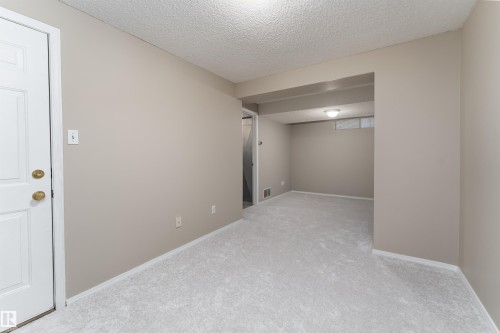 This room features neutral-toned walls, light-colored carpeting, and a white door with brass hardware - 3 9703 174 Street, Edmonton, AB - Indoor Photo Showing Other Room