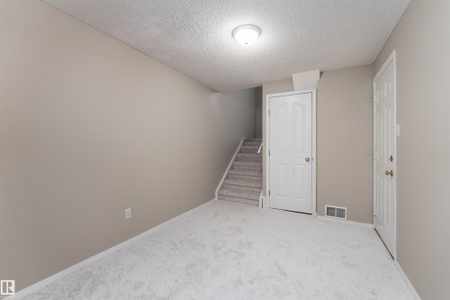 This area features light gray carpeting, neutral-toned walls, and a ceiling light fixture - 3 9703 174 Street, Edmonton, AB - Indoor Photo Showing Other Room