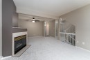 Living area featuring light-colored carpeting, a fireplace with a tiled surround, a ceiling fan, and a staircase with white railings - 3 9703 174 Street, Edmonton, AB  - Indoor With Fireplace 