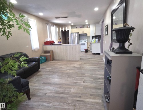 Open concept living area featuring wood-finish flooring, recessed lighting, and a kitchen with light-toned cabinetry, stainless steel appliances, and a central island - 10644 96 Street, Edmonton, AB - Indoor