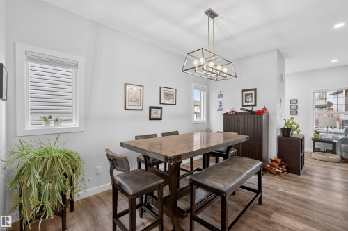 Dining area featuring wood-finish flooring and a contemporary linear chandelier - 53 Wingate Way, Fort Saskatchewan, AB - Indoor Photo Showing Dining Room