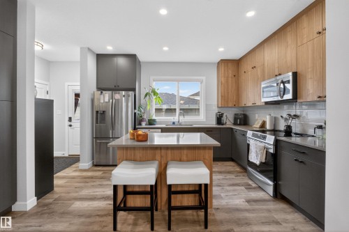Modern kitchen featuring a central island, wood-finish flooring, two-tone cabinetry, stainless steel appliances, and recessed lighting - 53 Wingate Way, Fort Saskatchewan, AB - Indoor Photo Showing Other Room