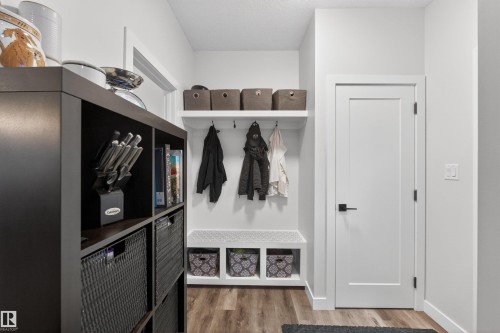 Entryway featuring wood-finish flooring, a white flat-panel door with black hardware, and a built-in bench with storage cubbies - 53 Wingate Way, Fort Saskatchewan, AB - Indoor Photo Showing Other Room