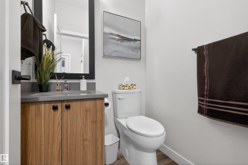 Bathroom featuring a wood-finish vanity with a gray countertop, a rectangular sink, and a black-framed mirror - 53 Wingate Way, Fort Saskatchewan, AB - Indoor Photo Showing Bathroom