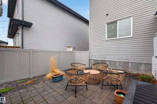 Paver patio courtyard featuring a privacy fence, gray siding, and a white-framed window - 53 Wingate Way, Fort Saskatchewan, AB - Outdoor With Deck Patio Veranda With Exterior