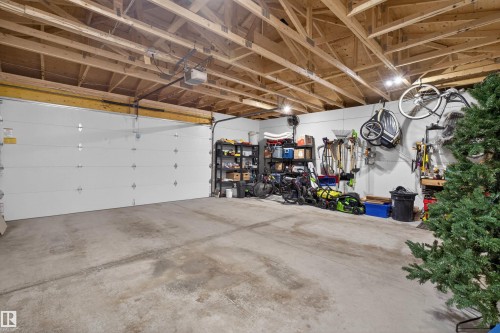 Spacious two-car garage featuring a concrete floor, exposed wood ceiling joists, and an automatic garage door opener - 53 Wingate Way, Fort Saskatchewan, AB - Indoor Photo Showing Garage