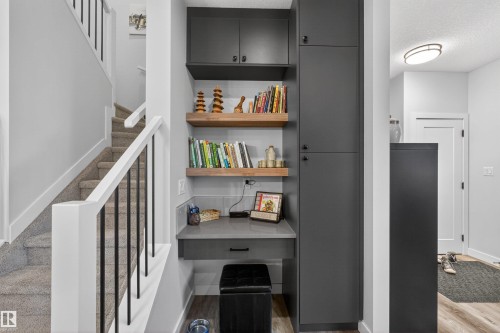 Built-in desk area featuring a gray countertop, wood-finish shelving, and integrated dark cabinetry - 53 Wingate Way, Fort Saskatchewan, AB - Indoor Photo Showing Other Room