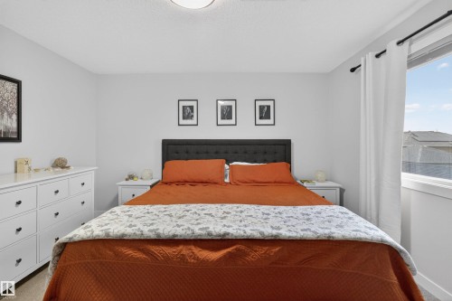 Bedroom featuring neutral wall colors, carpet flooring, a large window, and a ceiling-mounted light fixture - 53 Wingate Way, Fort Saskatchewan, AB - Indoor Photo Showing Bedroom
