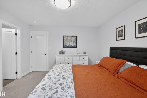 Carpeted bedroom featuring white walls, a flush-mount ceiling light, and white interior doors with dark hardware - 53 Wingate Way, Fort Saskatchewan, AB - Indoor Photo Showing Bedroom