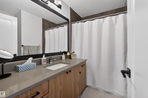 Bathroom vanity featuring a light gray countertop, integrated sink, and wood-finish cabinetry with matte black hardware - 53 Wingate Way, Fort Saskatchewan, AB - Indoor Photo Showing Bathroom