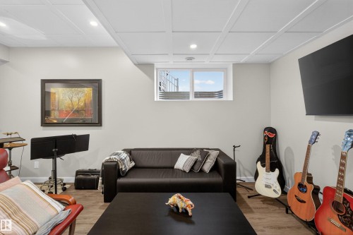 Finished lower level featuring recessed lighting, grid-pattern ceiling, wood-finish flooring, and a window with a window well - 53 Wingate Way, Fort Saskatchewan, AB - Indoor