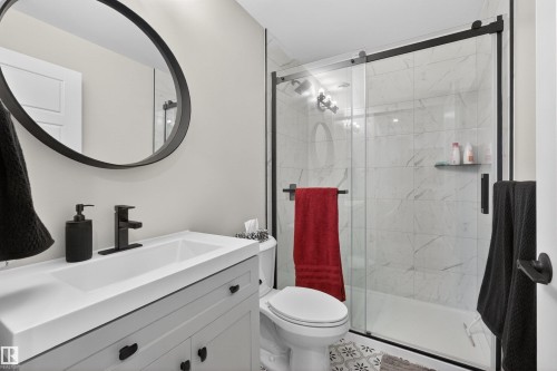 Contemporary bathroom featuring a vanity with an integrated sink, matte black faucet, and a round framed mirror - 53 Wingate Way, Fort Saskatchewan, AB - Indoor Photo Showing Bathroom