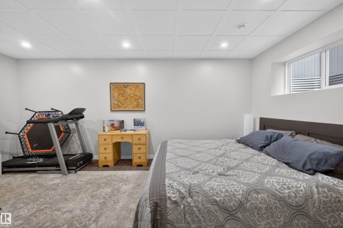 Spacious room featuring light gray walls, a grid-patterned ceiling with recessed lighting, and a window providing natural light - 53 Wingate Way, Fort Saskatchewan, AB - Indoor Photo Showing Bedroom