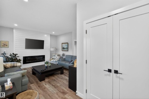 Living area featuring wood-finish flooring and a contemporary linear fireplace set into a shiplap accent wall - 53 Wingate Way, Fort Saskatchewan, AB - Indoor With Fireplace