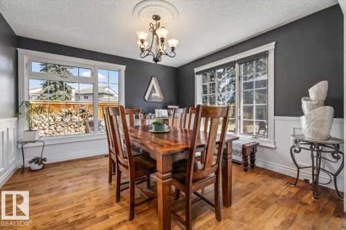 Dining area featuring wood-finish flooring, wainscoting, and large windows - 6003 176 Street, Edmonton, AB - Indoor Photo Showing Dining Room