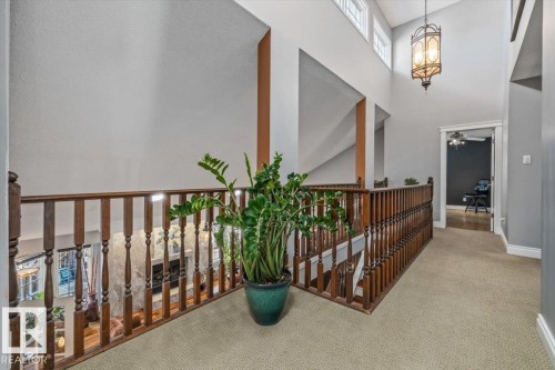 Upper-level hallway featuring wood spindle railing, carpet flooring, and a decorative hanging light fixture - 6003 176 Street, Edmonton, AB - Indoor Photo Showing Other Room