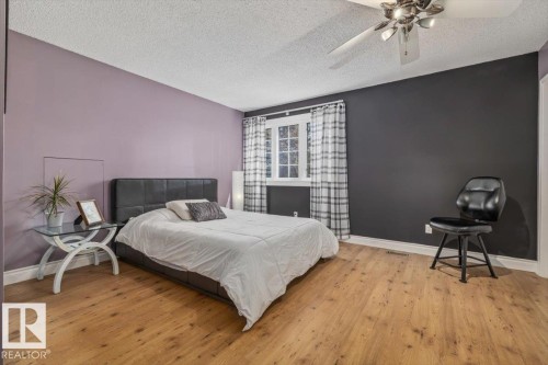 Bedroom featuring wood-finish flooring, a contemporary ceiling fan with integrated lighting, and a white framed window - 6003 176 Street, Edmonton, AB - Indoor Photo Showing Bedroom