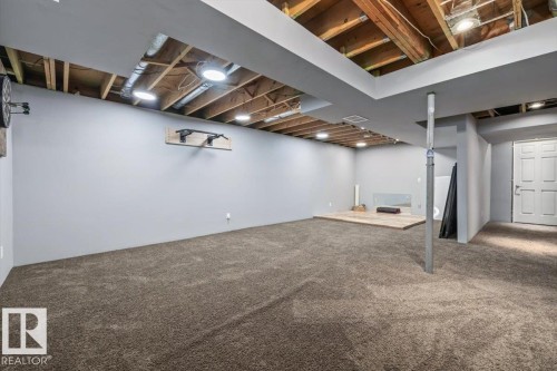 Expansive carpeted area with a partially finished ceiling featuring exposed joists and recessed lighting - 6003 176 Street, Edmonton, AB - Indoor