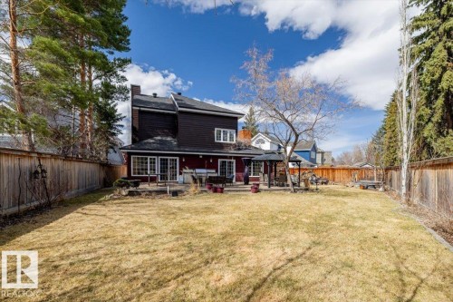 Spacious rear yard with a wooden fence boundary, mature trees, and a ground-level patio - 6003 176 Street, Edmonton, AB - Outdoor With Deck Patio Veranda