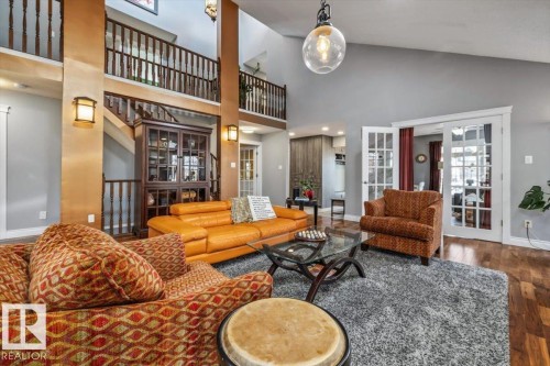 Vaulted ceilings with a prominent chandelier, wood-finish flooring, and French doors leading to an additional room - 6003 176 Street, Edmonton, AB - Indoor Photo Showing Living Room