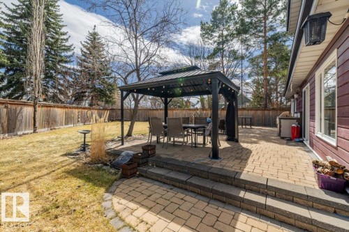 Expansive backyard featuring a multi-level paver patio, a black metal gazebo, and mature evergreen trees - 6003 176 Street, Edmonton, AB - Outdoor With Deck Patio Veranda