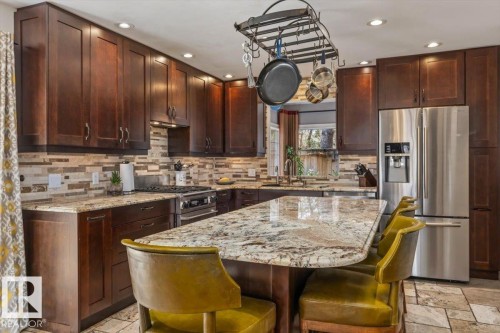 Kitchen with extensive dark wood cabinetry, a large center island with a stone countertop, and recessed lighting - 6003 176 Street, Edmonton, AB - Indoor