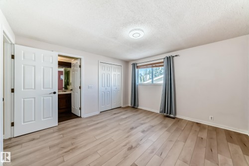 The property features hardwood floors, a window with grey curtains, and white paneled doors, including a closet with bi-fold doors - 4224 30 Street, Edmonton, AB - Indoor Photo Showing Other Room