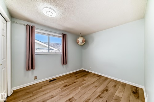 This room features light-toned walls, hardwood style flooring, and a window with curtains - 4224 30 Street, Edmonton, AB - Indoor Photo Showing Other Room
