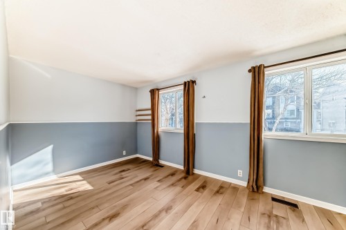 This room offers hardwood style flooring and two windows with curtains - 4224 30 Street, Edmonton, AB - Indoor Photo Showing Other Room