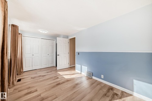 This room features light wood-style flooring, a large closet with white bi-fold doors, and a door with black hardware - 4224 30 Street, Edmonton, AB - Indoor Photo Showing Other Room